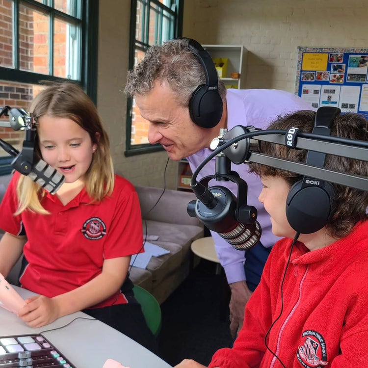 Two children and an adult using podcasting equipment