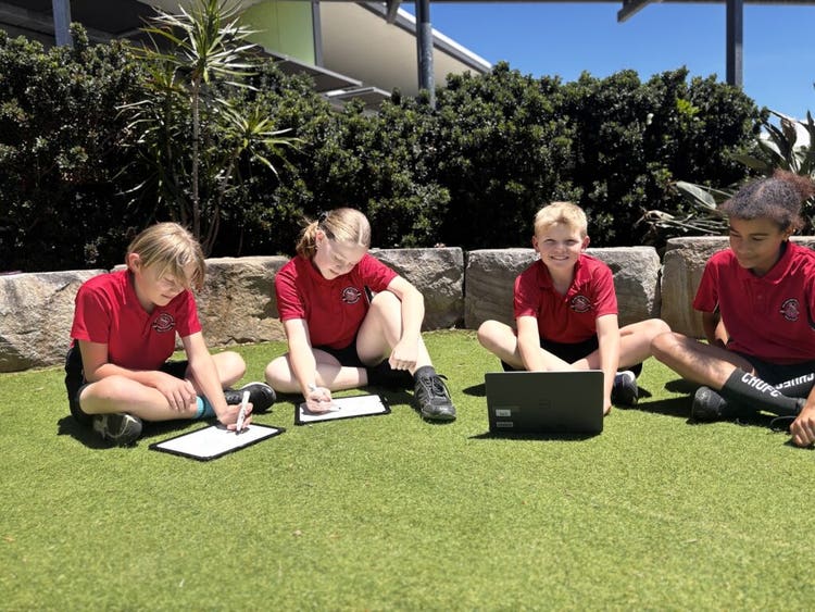 2 girls and 2 boys sitting in a circle on a grass area.